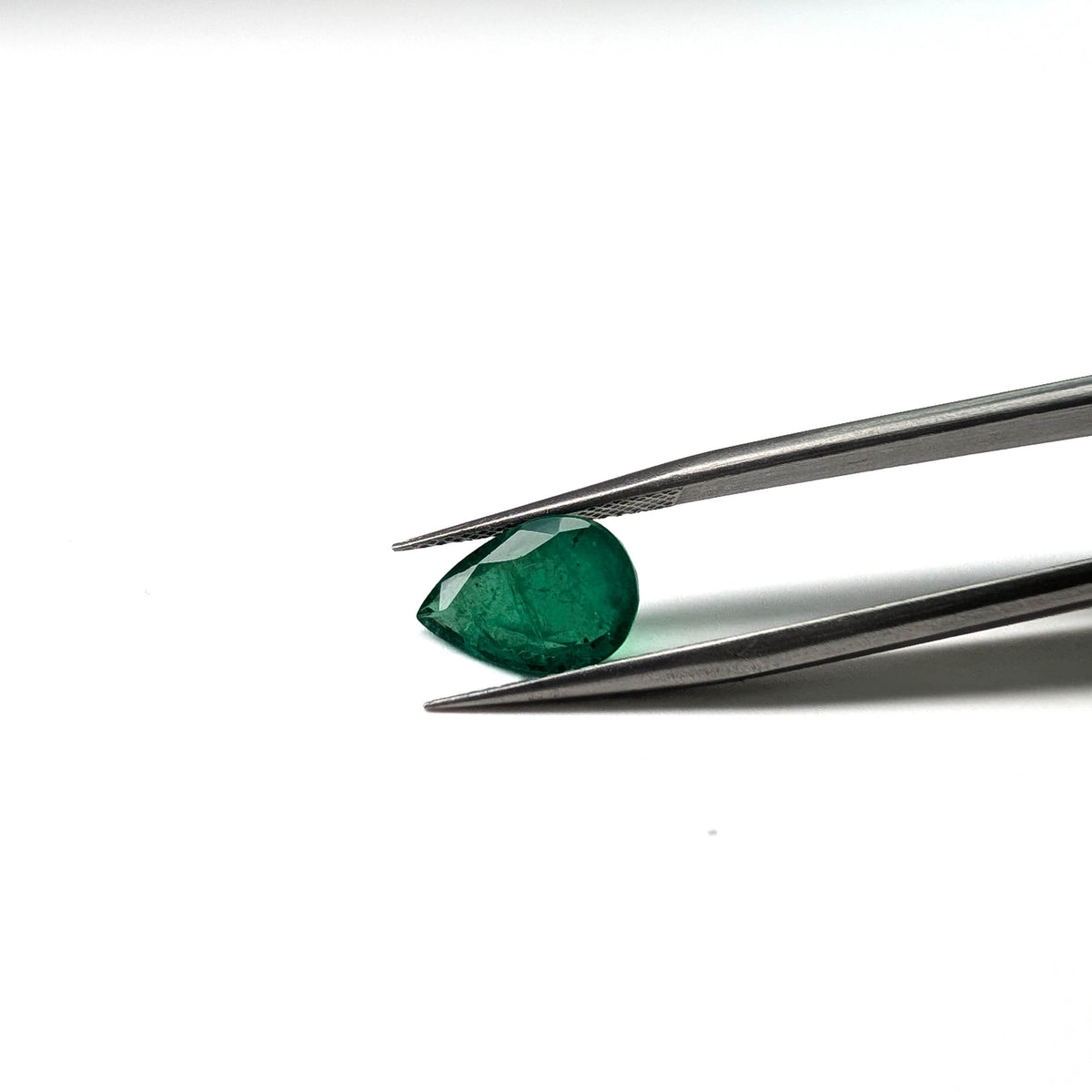 Emerald faceted pear cut gemstone, 2.57ct, held in tweezers, view 13 of 15