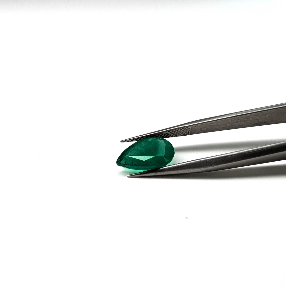 Emerald faceted pear cut gemstone, 2.57ct, held in tweezers, view 14 of 15