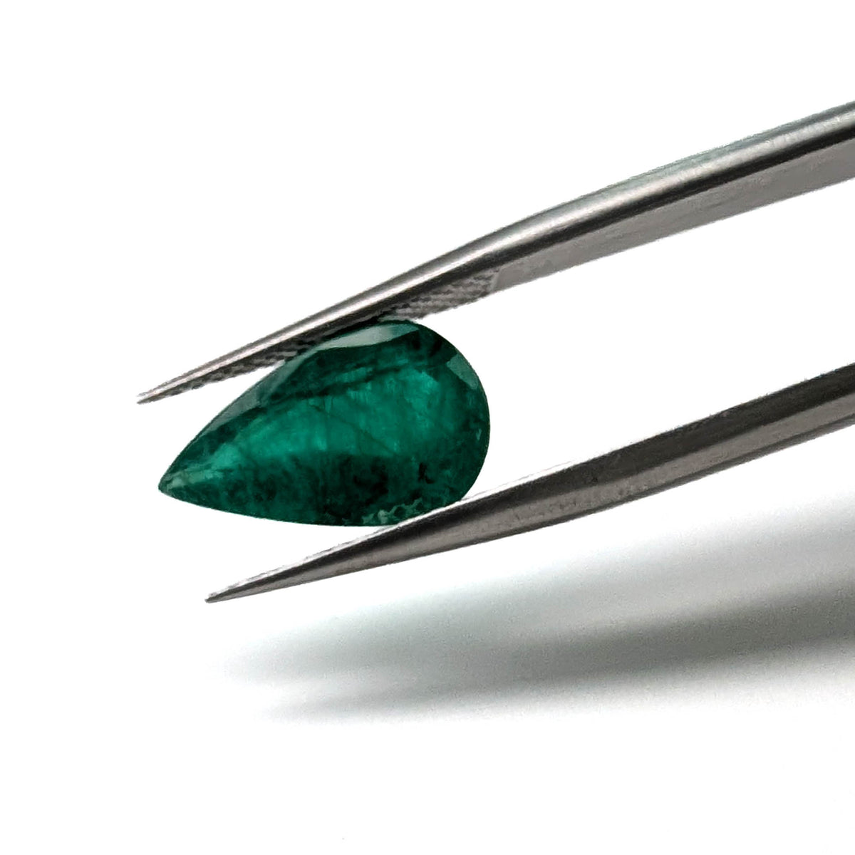 Emerald faceted pear cut gemstone, 2.62ct, held in tweezers, view 2 of 9
