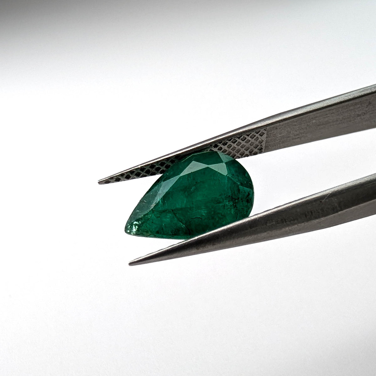 Emerald faceted pear cut gemstone, 2.66ct, held in tweezers, view 9 of 13