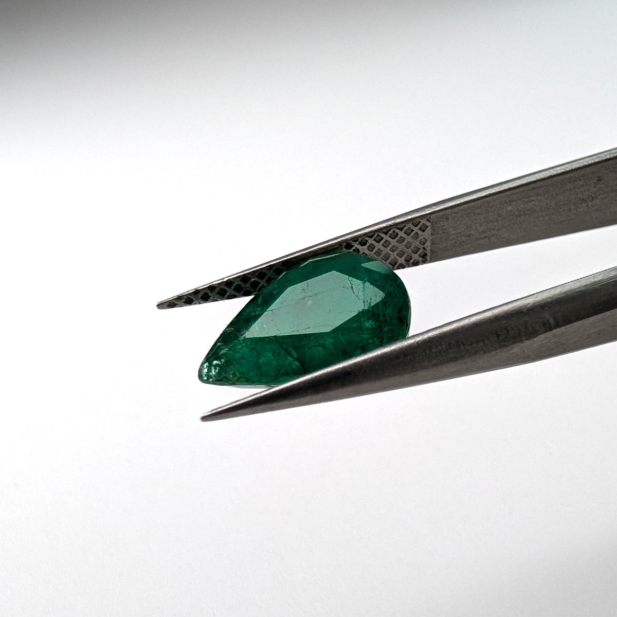 Emerald faceted pear cut gemstone, 2.66ct, held in tweezers, view 10 of 13