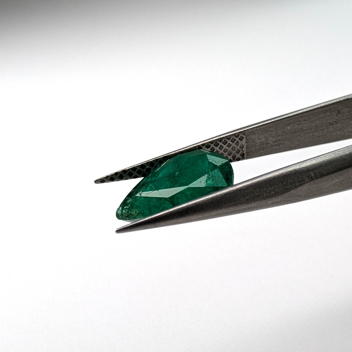 Emerald faceted pear cut gemstone, 2.66ct, held in tweezers, view 11 of 13