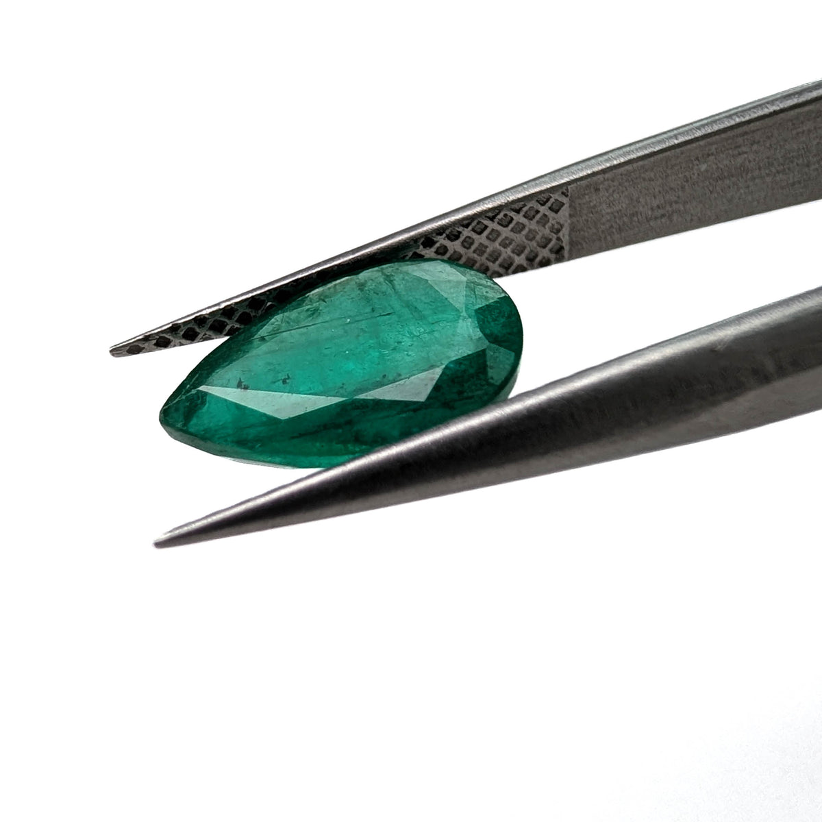Emerald faceted pear gemstone, 1.60ct, held in tweezers, angled view, view 10 of 11