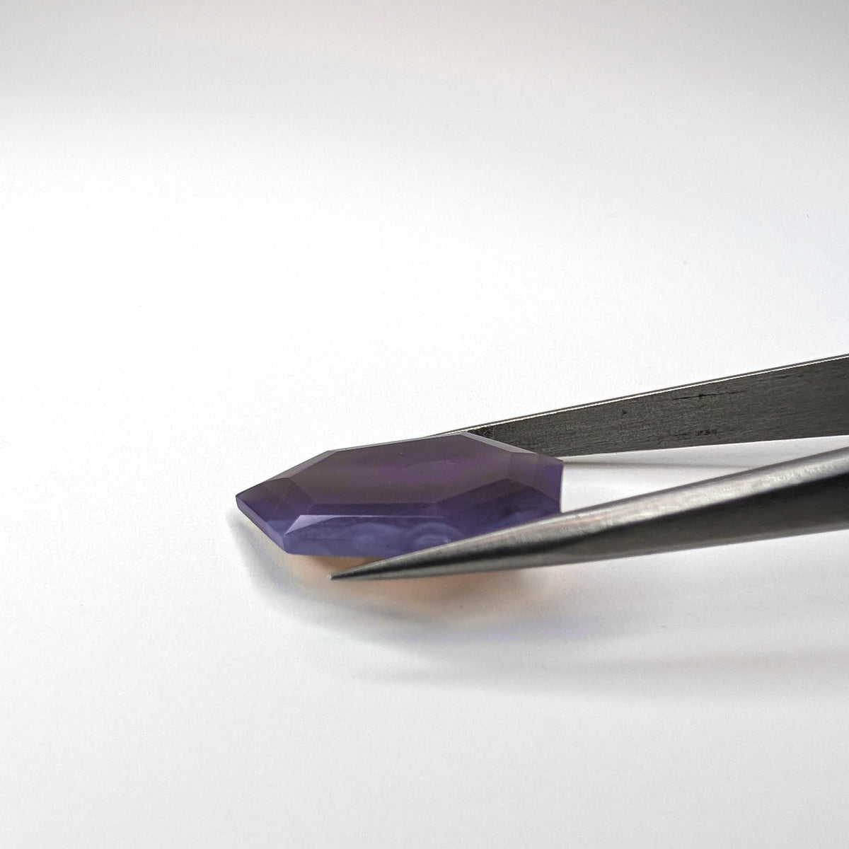 Holly Blue agate faceted freeform step tablet cut gemstone, 12.43ct, from Holley, Oregon, held in tweezers, view 8 of 13