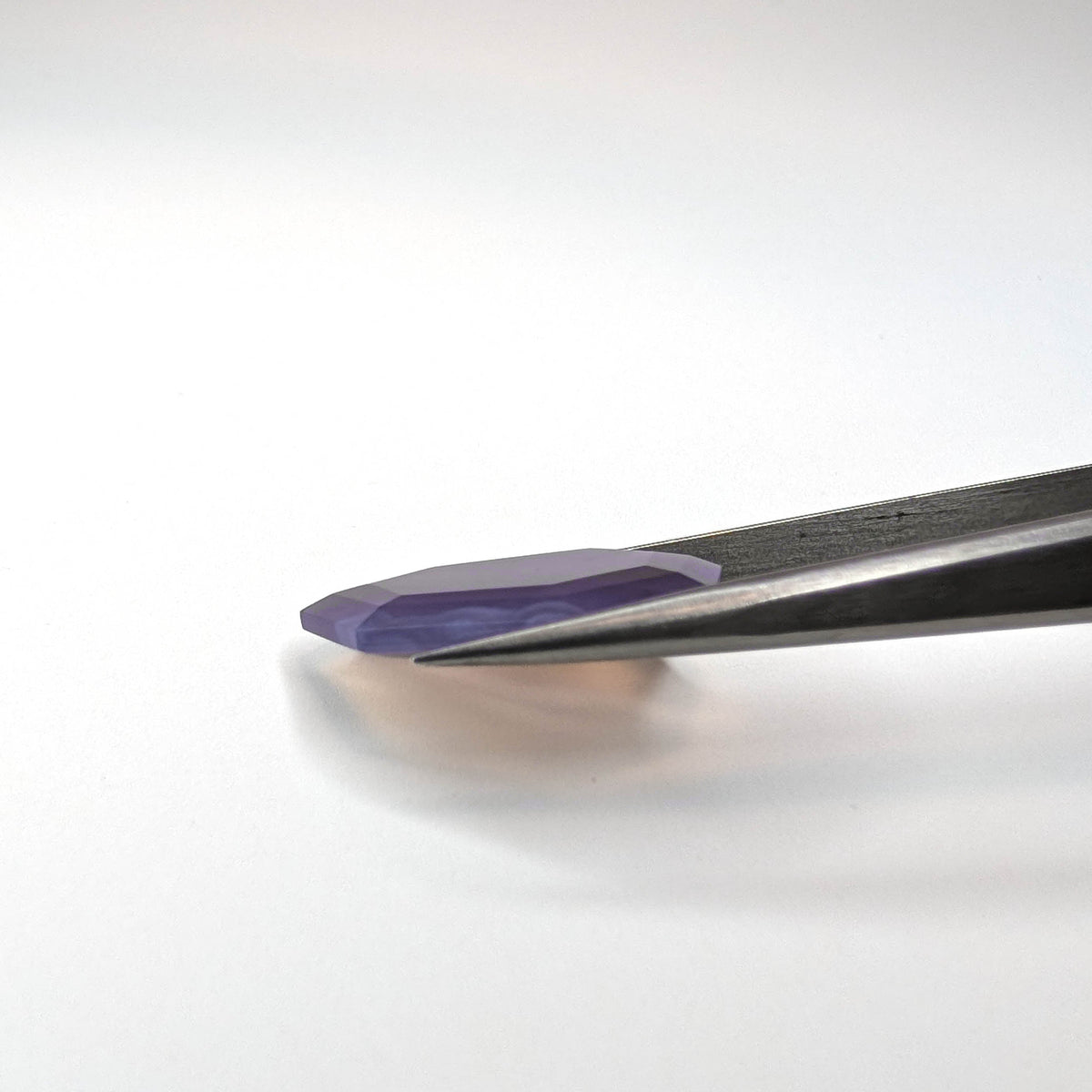Holly Blue agate faceted freeform step tablet cut gemstone, 12.43ct, from Holley, Oregon, held in tweezers, view 10 of 13