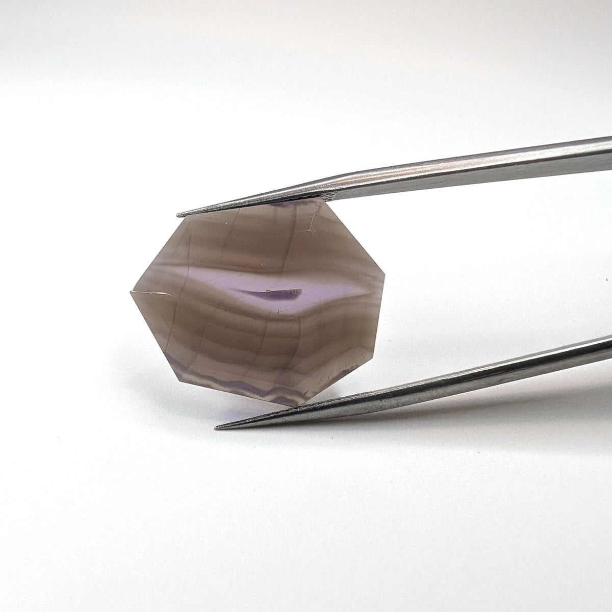 Holly Blue agate faceted freeform step tablet cut gemstone, 12.43ct, from Holley, Oregon, held in tweezers, view 11 of 13