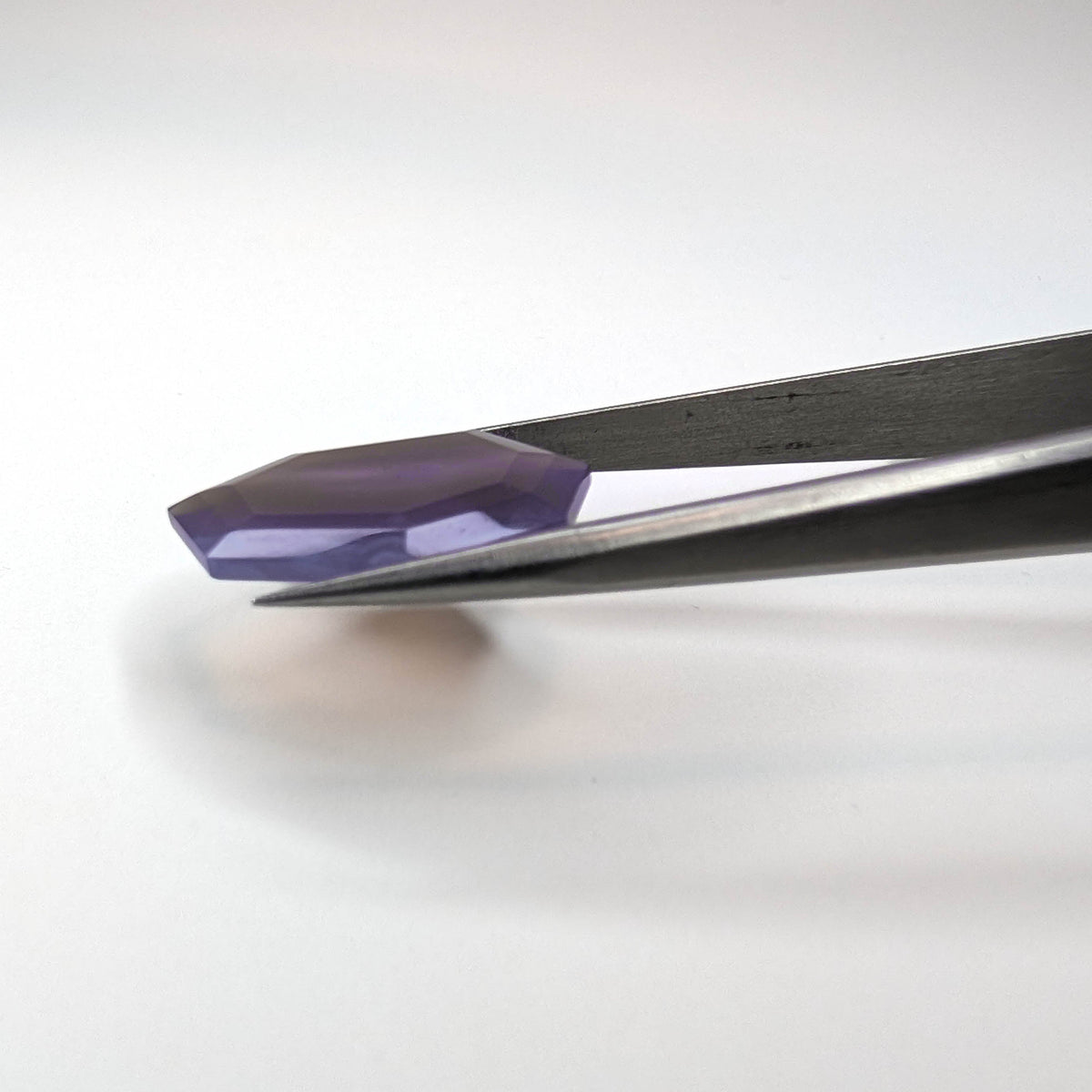 Holly Blue agate faceted freeform step tablet cut gemstone, 12.43ct, from Holley, Oregon, held in tweezers, view 12 of 13