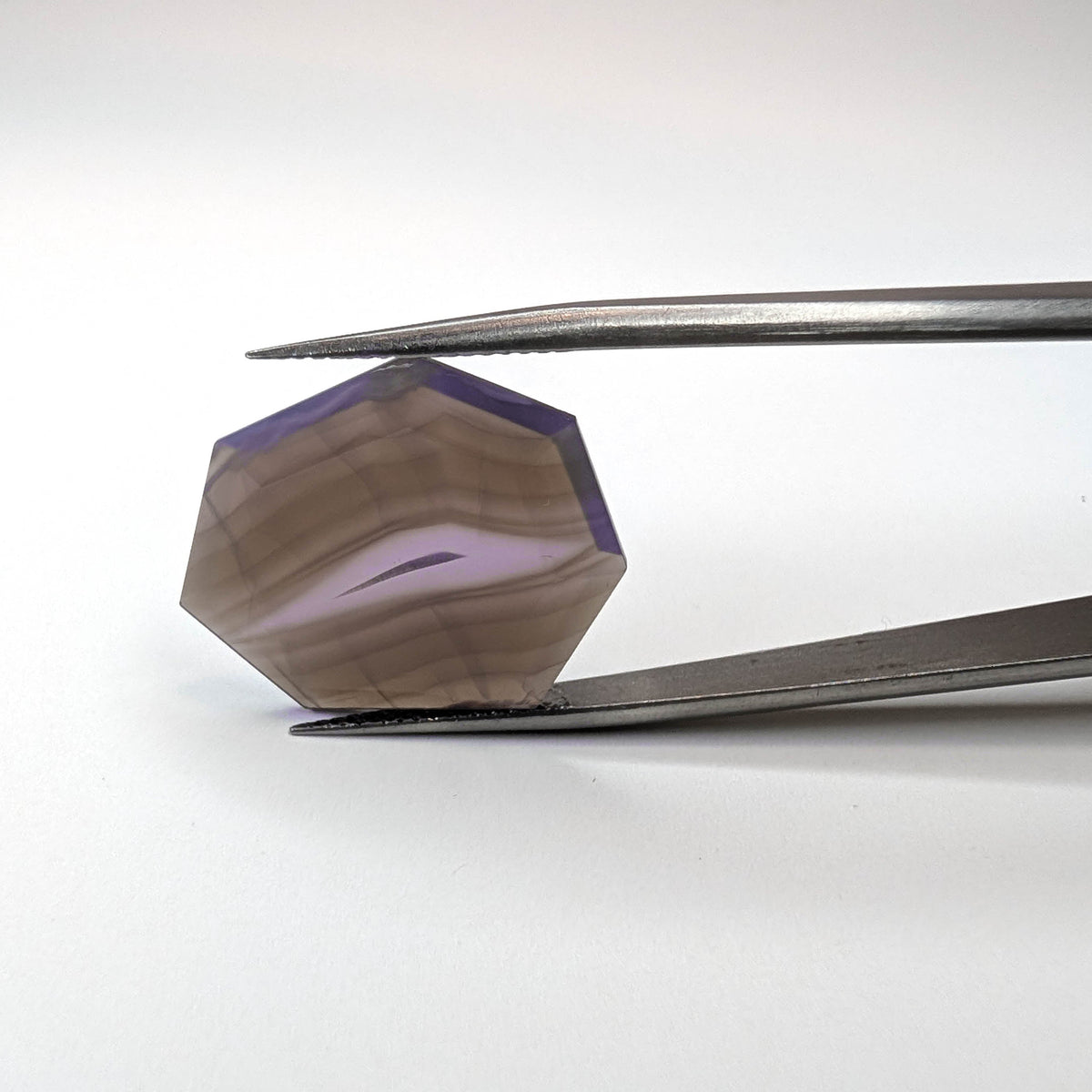 Holly Blue agate faceted freeform step tablet cut gemstone, 12.43ct, from Holley, Oregon, held in tweezers, view 13 of 13