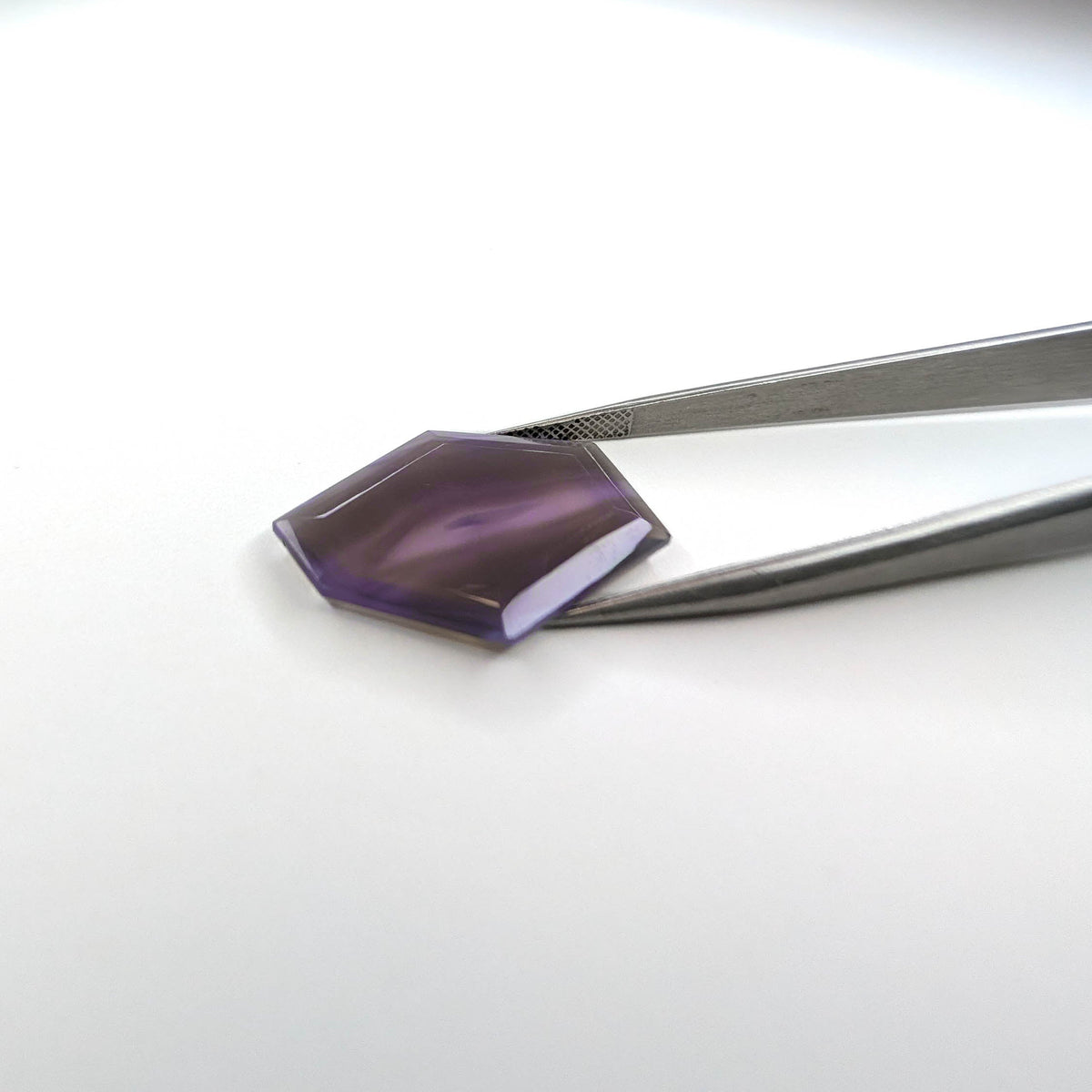 Holly Blue agate faceted freeform step tablet cut gemstone, 12.79ct, from Holley, Oregon, held in tweezers, view 2 of 10