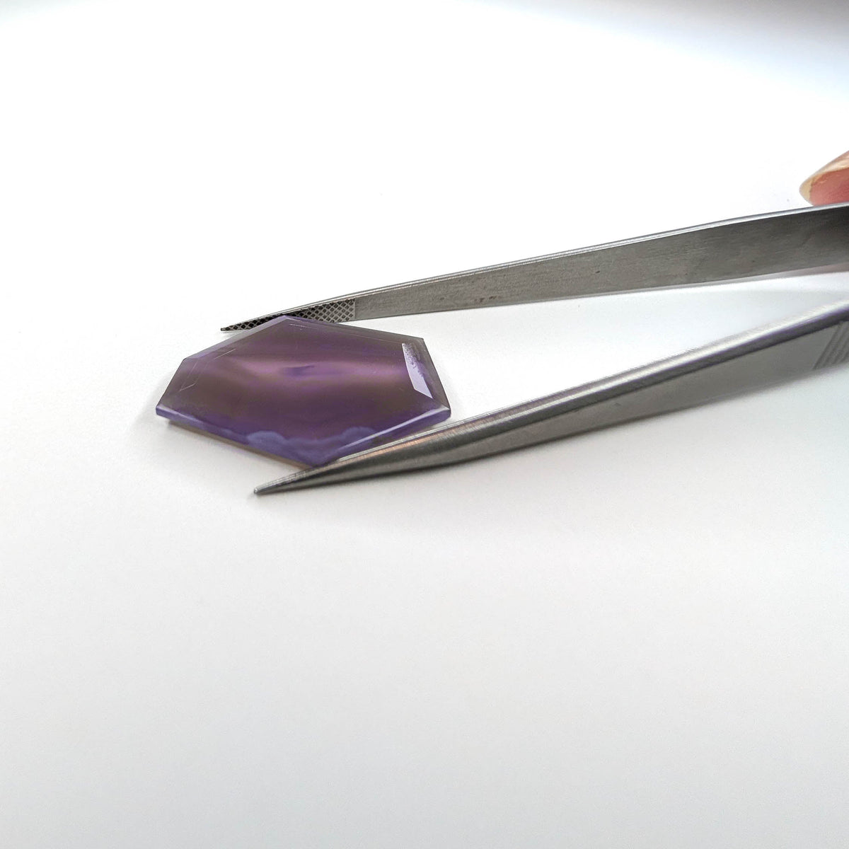 Holly Blue agate faceted freeform step tablet cut gemstone, 12.79ct, from Holley, Oregon, held in tweezers, view 9 of 10
