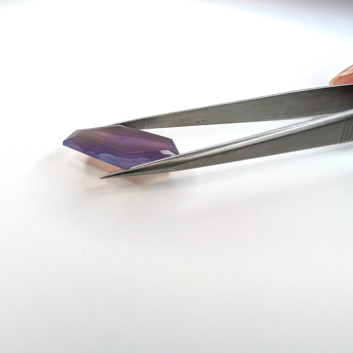 Holly Blue agate faceted freeform step tablet cut gemstone, 12.79ct, from Holley, Oregon, held in tweezers, view 10 of 10