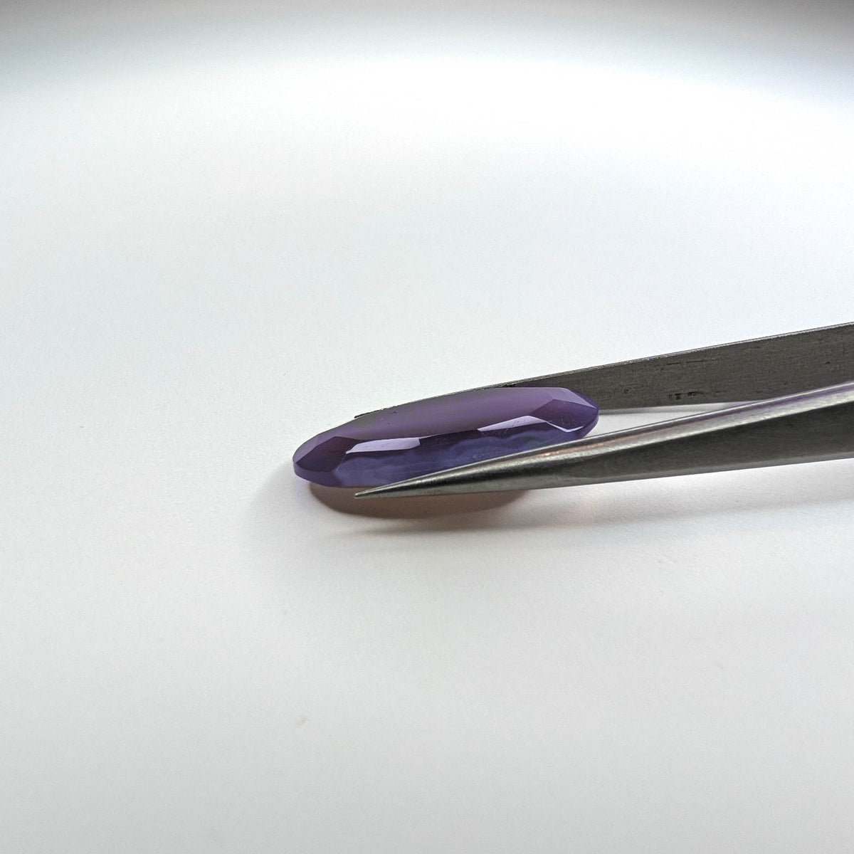 Holly Blue agate faceted egg step tablet cut gemstone, 14.08ct, from Holley, Oregon, held in tweezers, view 9 of 9