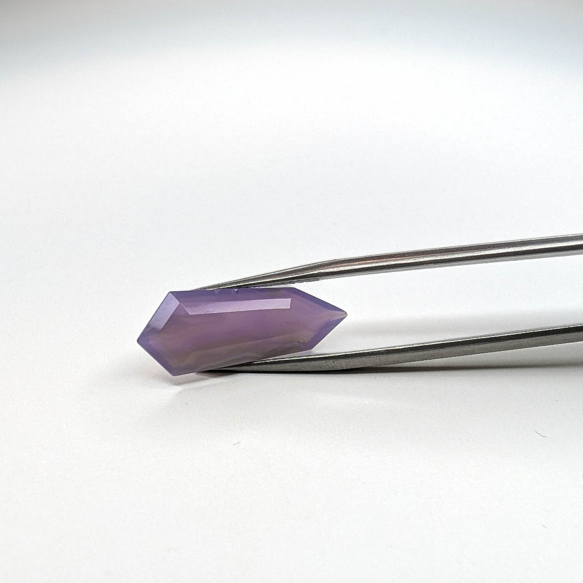 Holly Blue agate faceted freeform step tablet cut gemstone, 6.18ct, from Holley, Oregon, held in tweezers, view 7 of 8