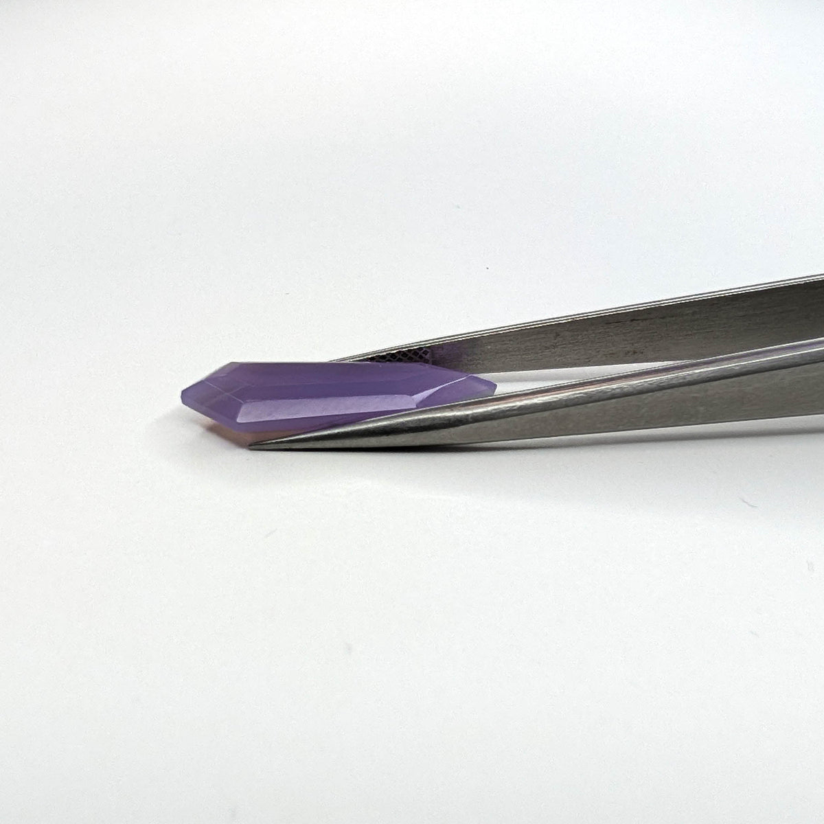 Holly Blue agate faceted freeform step tablet cut gemstone, 6.18ct, from Holley, Oregon, held in tweezers, view 8 of 8