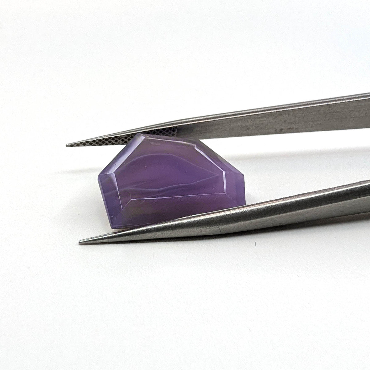 Holly Blue agate faceted freeform step tablet cut gemstone, 8.49ct, from Holley, Oregon, held in tweezers, view 2 of 11