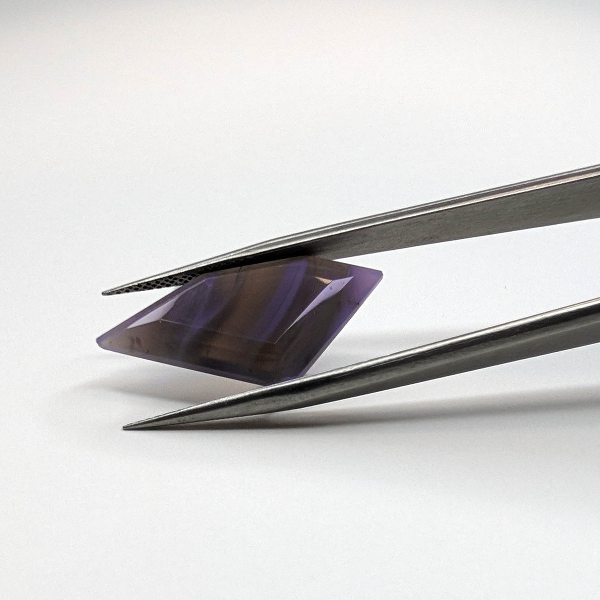 Holly Blue agate faceted freeform step tablet cut gemstone, 8.92ct, from Holley, Oregon, held in tweezers, view 6 of 9