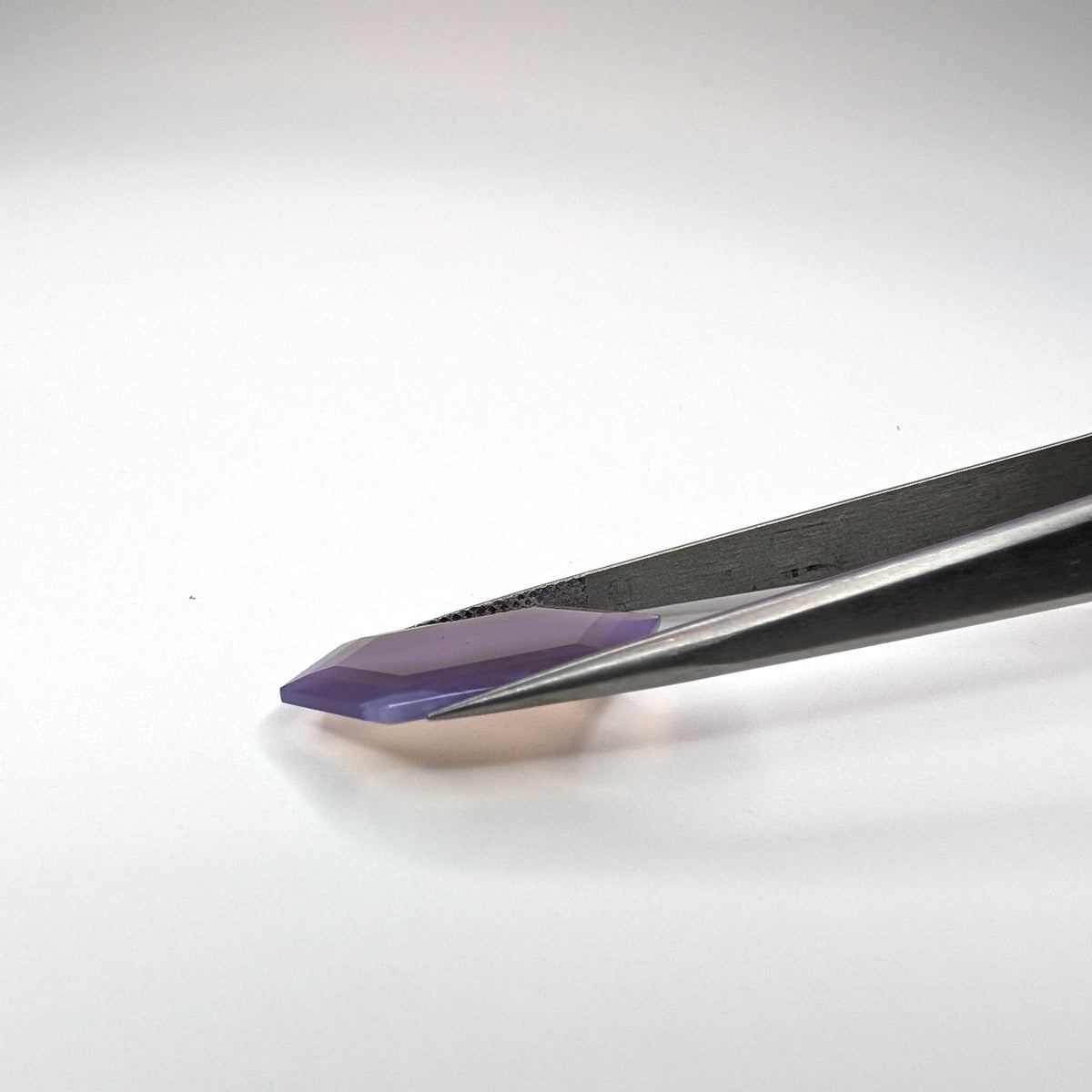 Holly Blue agate faceted freeform step tablet cut gemstone, 8.99ct, from Holley, Oregon, held in tweezers, view 4 of 6