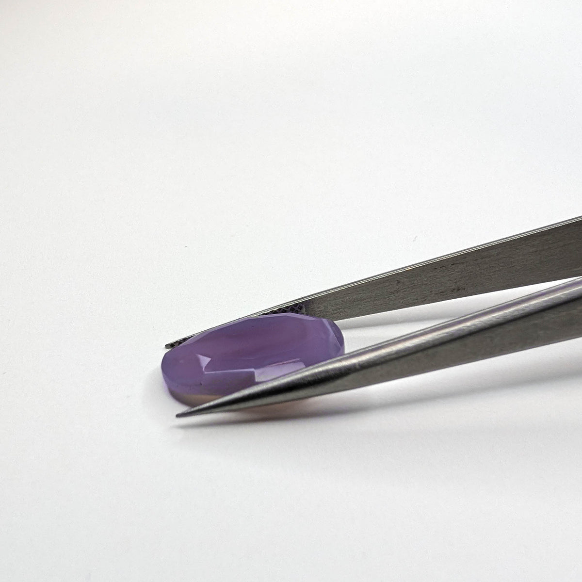 Holly Blue agate faceted egg step tablet cut gemstone, 6.32ct, from Holley, Oregon, held in tweezers, view 10 of 10