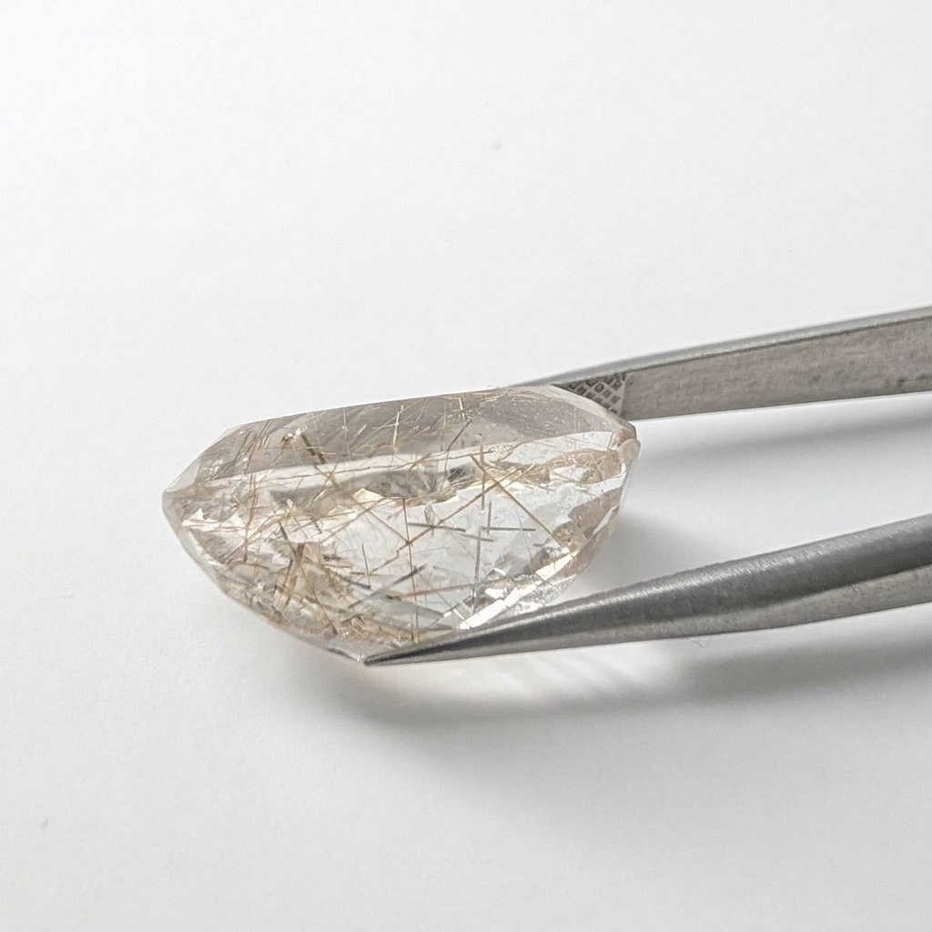 Actinolite quartz faceted oval gemstone, 17.09ct, from Mount Breakenridge, Harrison Lake, BC, Canada, held in tweezers, view 2 of 8
