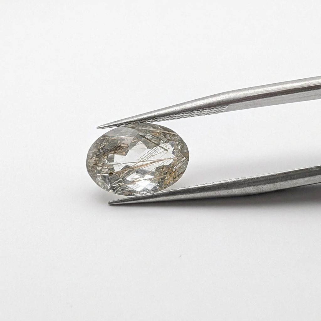 Actinolite quartz faceted oval gemstone, 3.65ct, from Mount Breakenridge, Harrison Lake, BC, Canada, held in tweezers, view 2 of 11