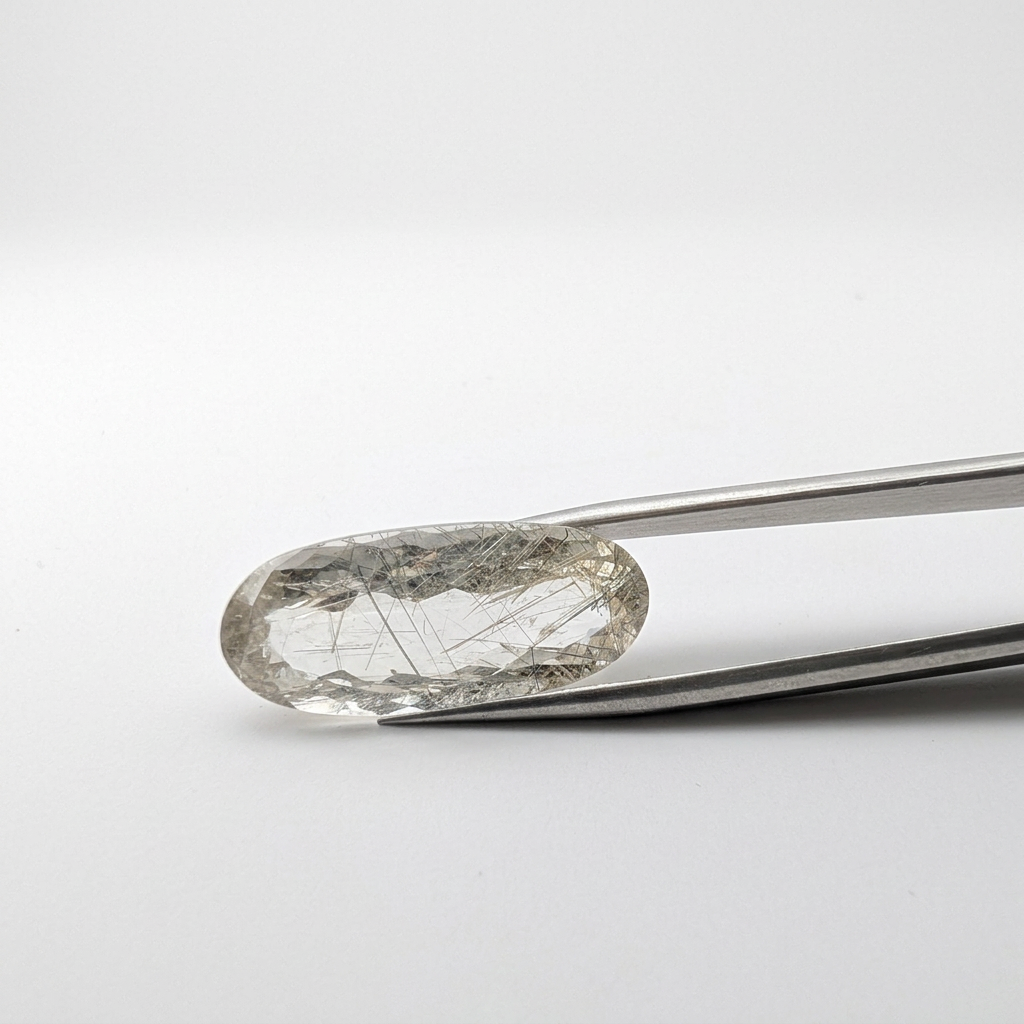 Actinolite quartz faceted oval gemstone, 15.08ct, from Mount Breakenridge, Harrison Lake, BC, Canada, held in tweezers, view 2 of 11