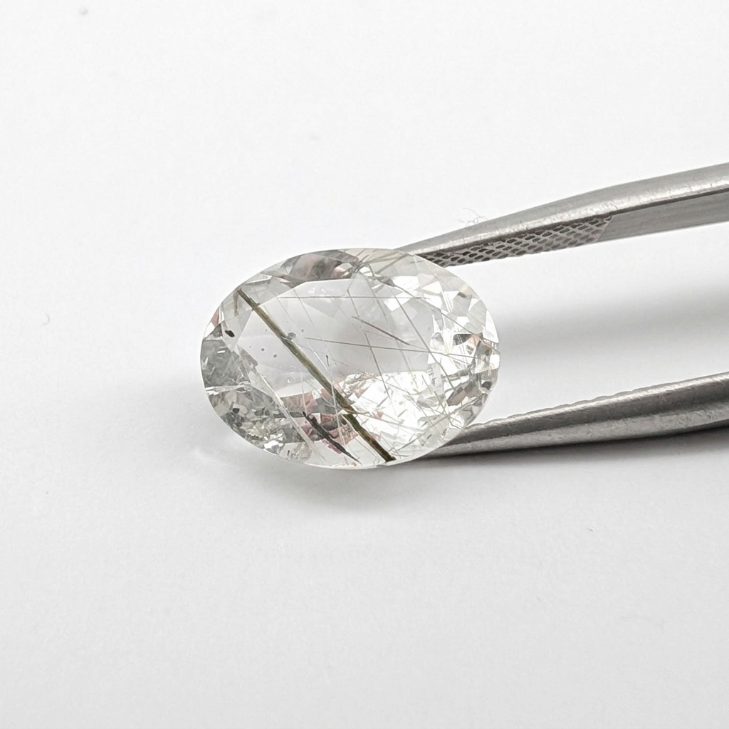 Actinolite quartz faceted oval gemstone, 6.02ct, from Mount Breakenridge, Harrison Lake, BC, Canada, held in tweezers, view 2 of 14