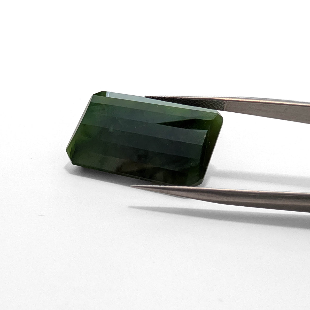 Nephrite Jade faceted emerald gemstone, 46.32ct, held in tweezers