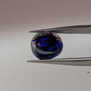 Black opal cabochon freeform gemstone, 2.67ct, from Lightning Ridge, New South Wales, Australia, held in tweezers, view 2 of 5