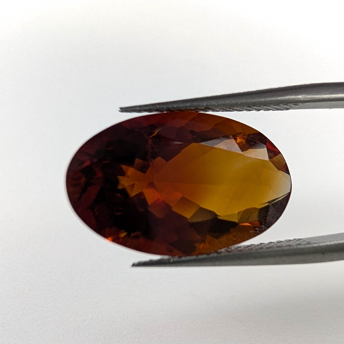 Oregon Sunstone faceted oval cut gemstone, 8.00ct, from Plush, Oregon, held in tweezers, view 2 of 8