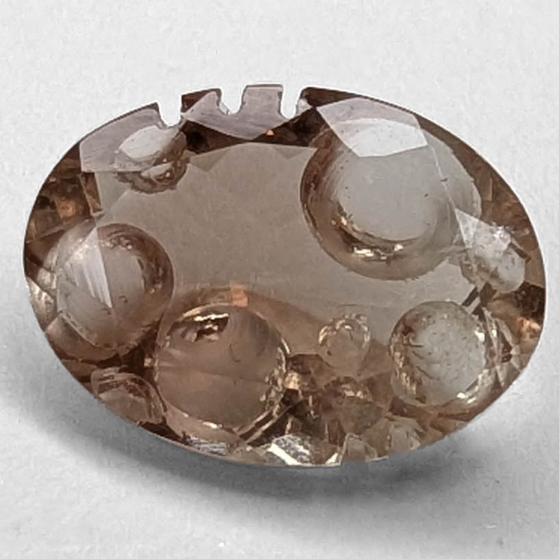 Oregon Sunstone faceted oval fantasy cut gemstone, 2.20ct, from Plush, Oregon, on a white background, view 1 of 11