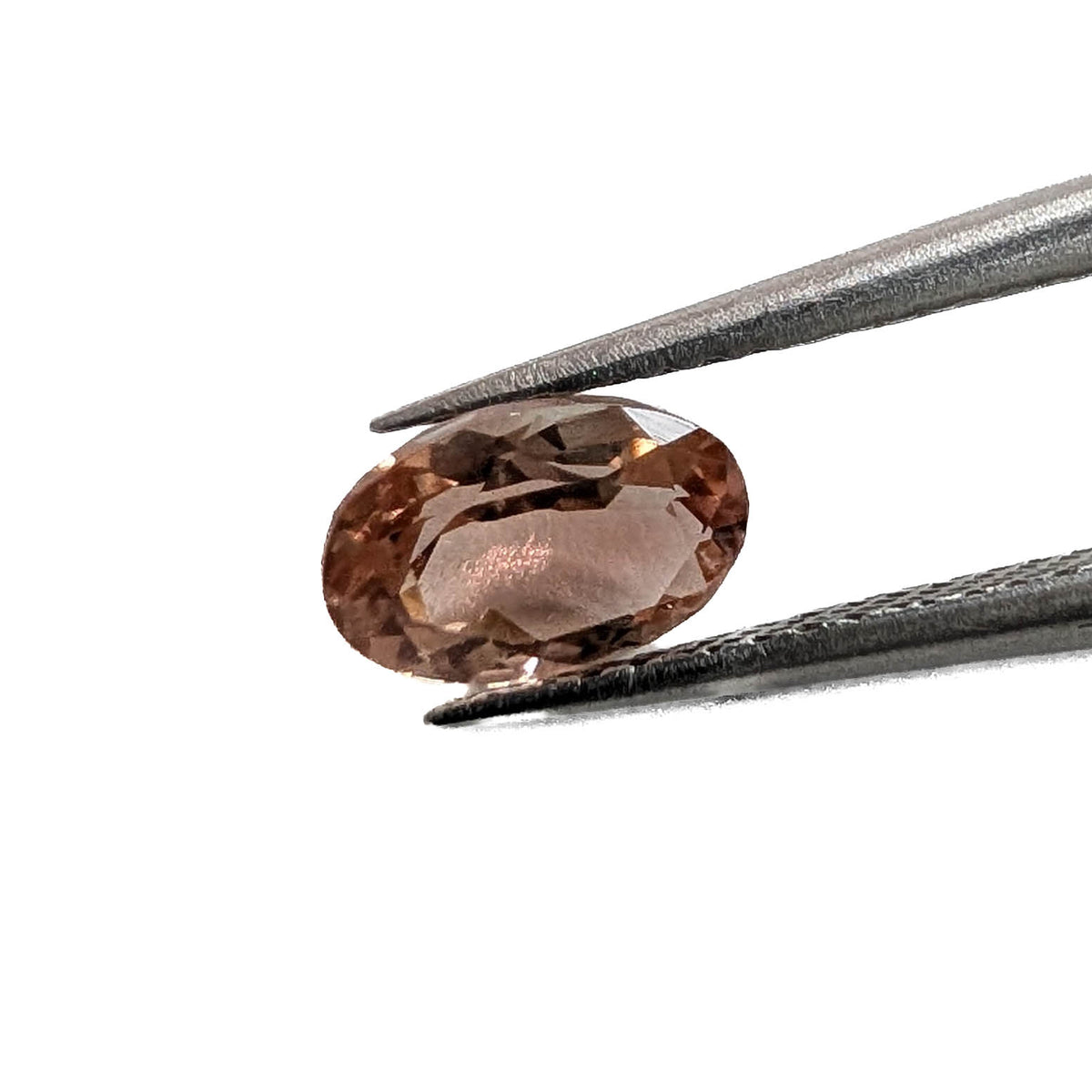 Oregon sunstone faceted oval gemstone, 5.05ct, held in tweezers
