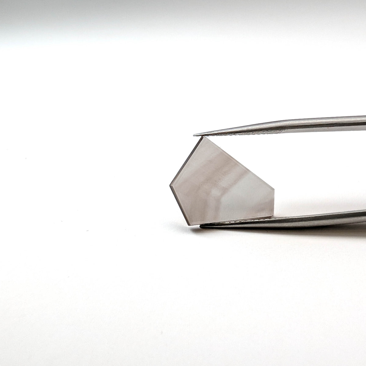 Smoky Quartz faceted freeform flatback step cut gemstone, 4.32ct, from Minas Gerais, Brazil, held in tweezers, view 6 of 7