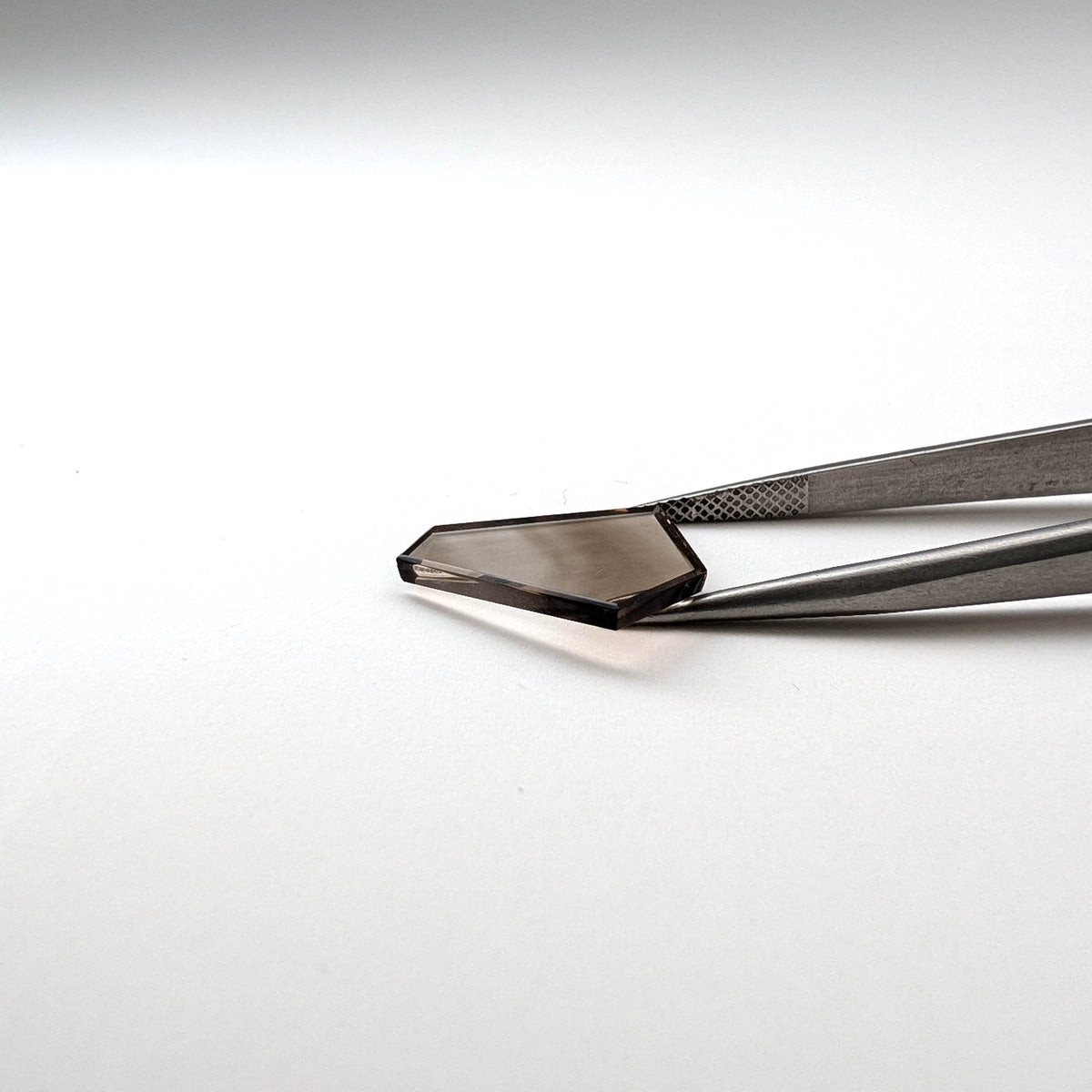 Smoky Quartz faceted freeform flatback step cut gemstone, 4.32ct, from Minas Gerais, Brazil, held in tweezers, view 7 of 7